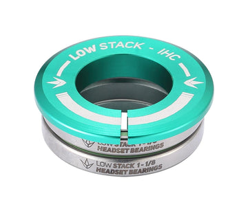 The Blunt Envy Low Stack IHC Integrated Stunt Scooter Headset in teal features sealed bearings and a distinctive arrow symbol. Its "LOW STACK - IHC" and "LOW STACK 1-1/8 HEADSET BEARINGS" labeling enhances its compatibility with the Blunt Envy Stunt Scooter, offering a sleek metallic finish through neatly stacked components.