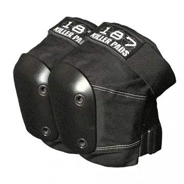 A pair of 187 Killer Slim Knee Skate Protection Pads in black, featuring hard plastic caps and adjustable straps, is set against a white background. Each pad displays the "187" label in white text, showcasing their exceptional skate protection with a memory foam system for added comfort.