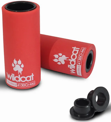 Two Wildcat Pro Mini BMX Pegs - Red by Wildcat are shown side by side with small black axle adaptors and peg sleeves on a clean white background. The durable chromoly pegs feature bold white Wildcat branding.