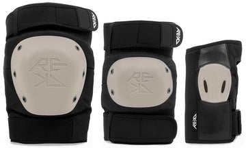 The REKD Shield Triple Skate Protection Pad Set in Black/Beige includes a knee pad and elbow pad with beige hard shells, plus a wrist guard with a high-impact palm splint—all offering premium action sports protection and featuring the REKD logo.