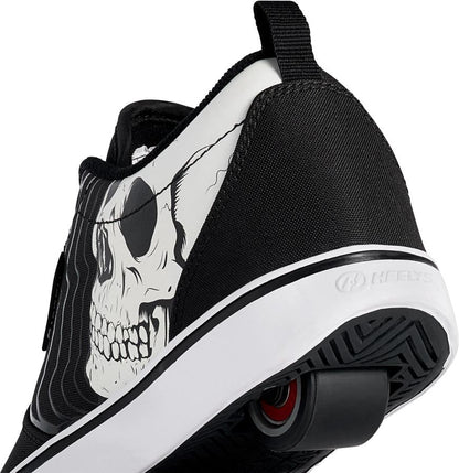 A close-up of the Heelys Pro 20 PRNT Glow Boys Shoes by Heelys in black/white, showing a glow-in-the-dark skull graphic on the side and low-profile wheels in the sole for smooth rolling.