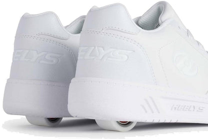 The Heelys Kama Girls Shoes in white feature low-profile wheels in the heels, blending classic court-style design with fun mobility. Shown from back and side views on a white background. Brand: Heelys.