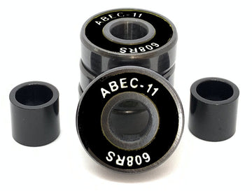 A set of four Logic ABEC 11 Black Scooter Bearings is shown, with one bearing turned to display its label. These high-performance bearings, from the brand Logic, include two cylindrical spacers positioned on each side against a white background, emphasizing their speed capabilities.