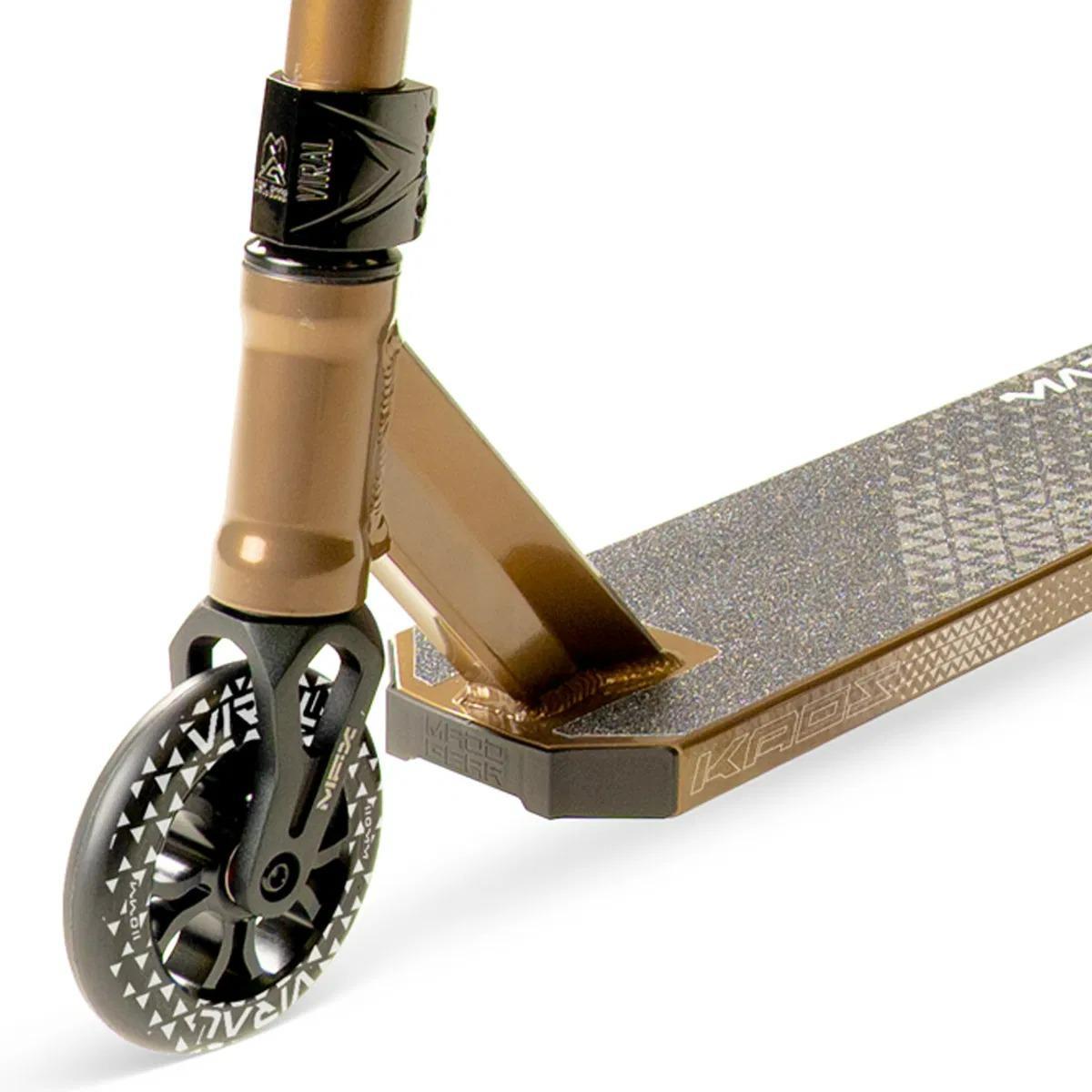 Close-up of the Ash-colored Madd Gear Viral KAOS Complete Stunt Scooter showing the front wheel with patterned spokes, sturdy fork, clamp, and textured deck for grip. Brand: Madd Gear (MGP).
