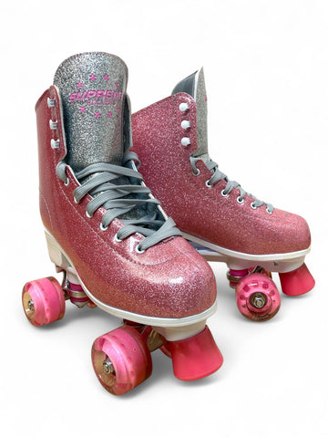 The Supreme Del Rey Adjustable Quad Roller Skates - Pink by Supreme feature sparkly pink glitter, gray laces, pink wheels, and silver glittery tongues, shown against a white background.
