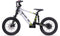 The Duo 18" Blitz Kids Electric Balance Bike in white and black features thick knobby tires, front and rear suspension, disc brakes, and green accents. Shown side profile on a white background. Brand: Duo.
