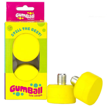 The packaging for the Gumball Roller Skate Short 17mm 75A Toe Stops - Lemon Yellow showcases two stops, one upright and one partially nestled. The vibrant pink and yellow box features "Gumball" and "Still the Best!"—ideal for improving skating control with high-performance toe stops.