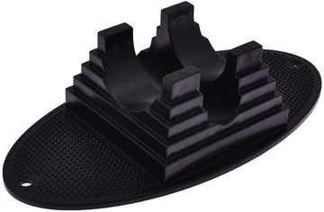 The Dial 911 Stunt Scooter Stand in black is an oval-shaped rubber pad with central pyramid structures, designed to hold items securely. It is ideal as a scooter stand, featuring a textured base and two holes on either end to ensure an upright position.