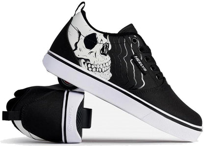 Heelys Pro 20 PRNT Glow Boys Shoes in black and white by Heelys feature low-profile wheels and a glow-in-the-dark skull graphic. One shoe stands upright, the other is angled to show the wheels in the heel.