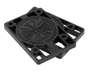 A pair of Independent Skateboard Riser Pads (1/8") in black, complete with the iconic Indy trucks logo embossed on them. These custom-molded risers feature a circular design in the center and multiple holes for easy mounting.