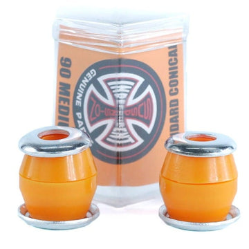 Two Independent Standard Conical Orange Skateboard Bushings, featuring a conical design and paired with silver metal washers, are positioned in front of branded packaging showcasing a black and red Independent logo. These bushings are crafted from high rebound urethane to deliver outstanding performance on your skateboard.