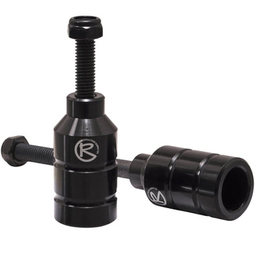 Two black Revolution Aluminium Stunt Scooter Pegs, designed from CNC milled aluminum, feature a cylindrical shape with a bolt on top for easy installation and the "R" logo on the side. Built to enhance your scooter's performance and durability, they offer precision engineering for stunts.