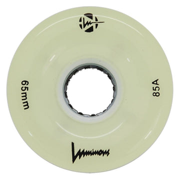 A cream-colored Luminous LED 85A Quad Roller Skate Wheel (White Glow, 65mm) has "65mm" and "85A durometer" printed on it, a central axle hole, the Luminous brand name, and black logos.